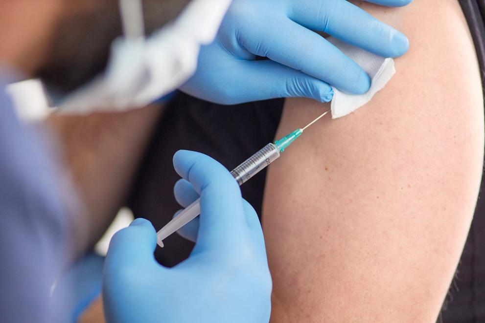 A picture of a vaccine being administered to someone's arm through a needle