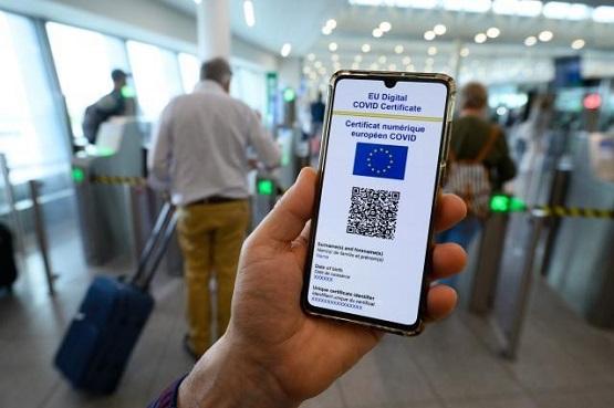 Person's hand holding a digital COVID certificate at an airport