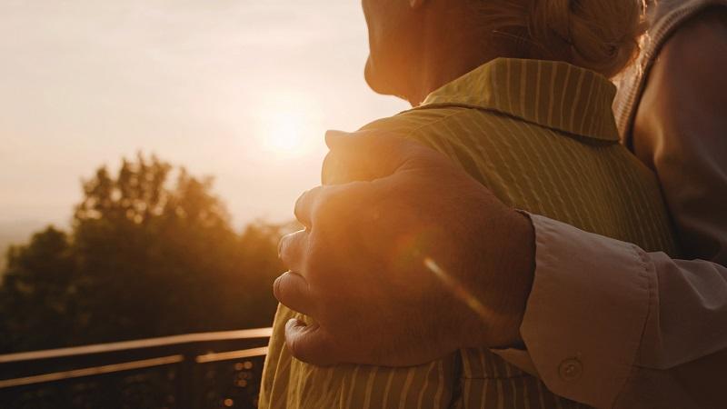Loving husband hugging wife in park, retired couple looking at sunset together