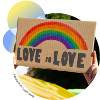 A person holding a poster with a rainbow and the words "Love is Love"