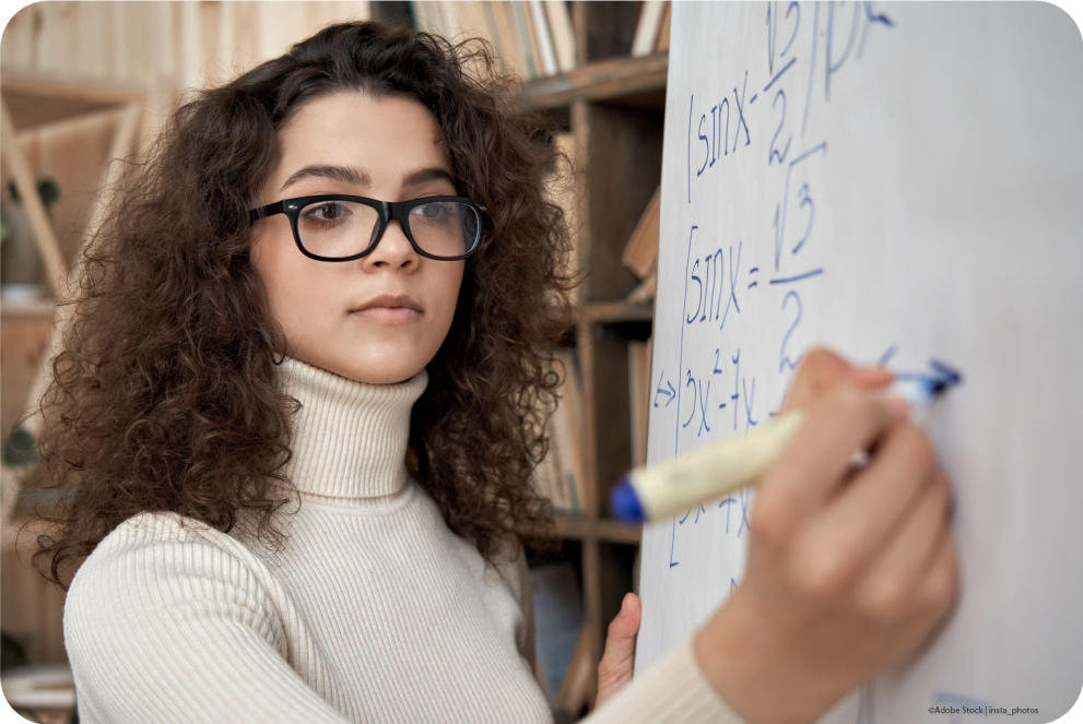 A young woman does scientific calculations on a whiteboard