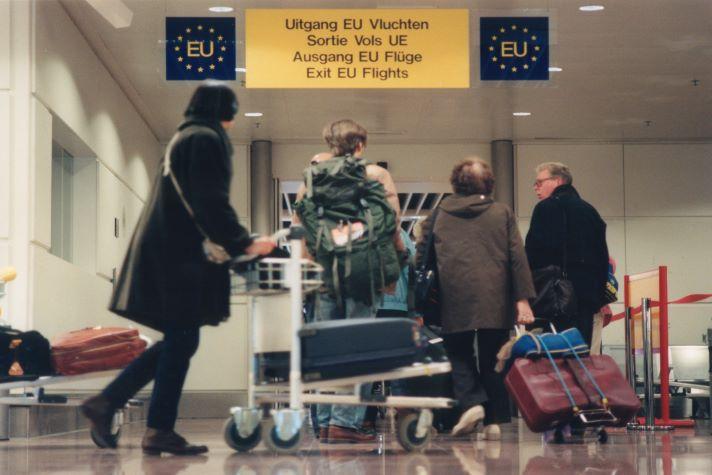 Four people entering with luggage trollies the EU border controls at an airport