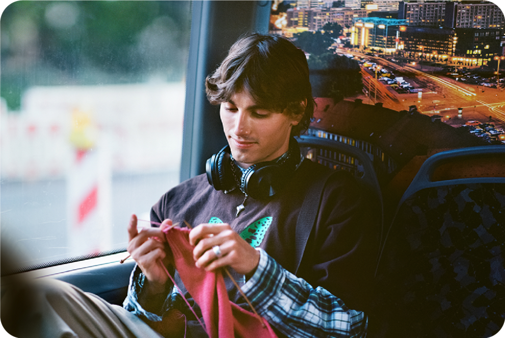 a man is knitting in the bus