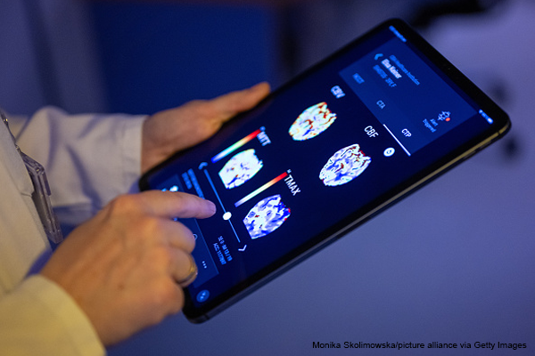A radiologist looks at a patient's brain images in an AI-based app on a tablet