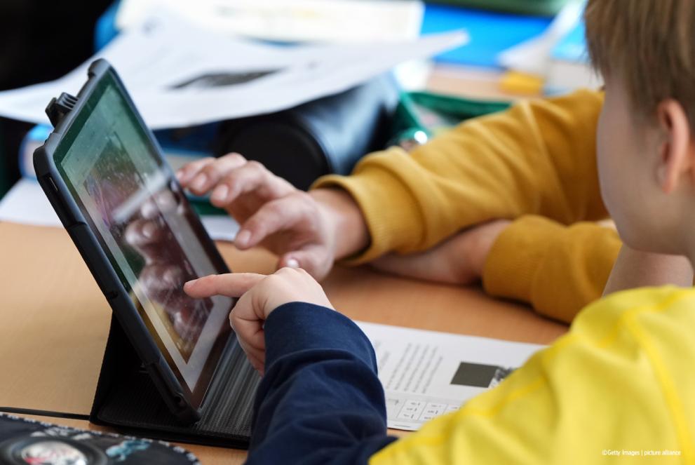 Учитель и ученик вместе используют планшет в классе.