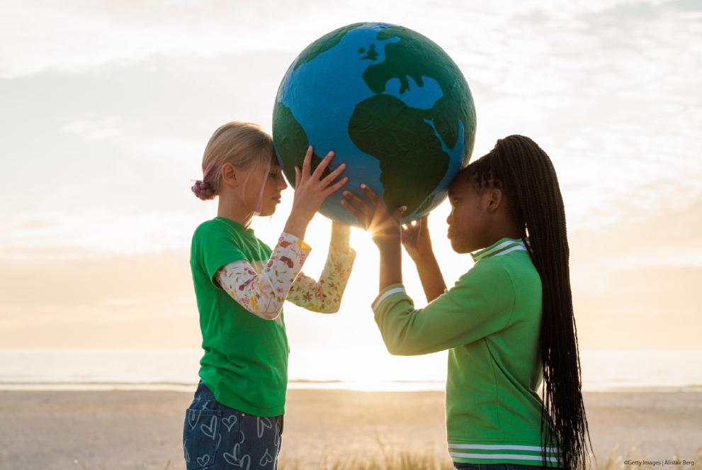 two children holding a world map