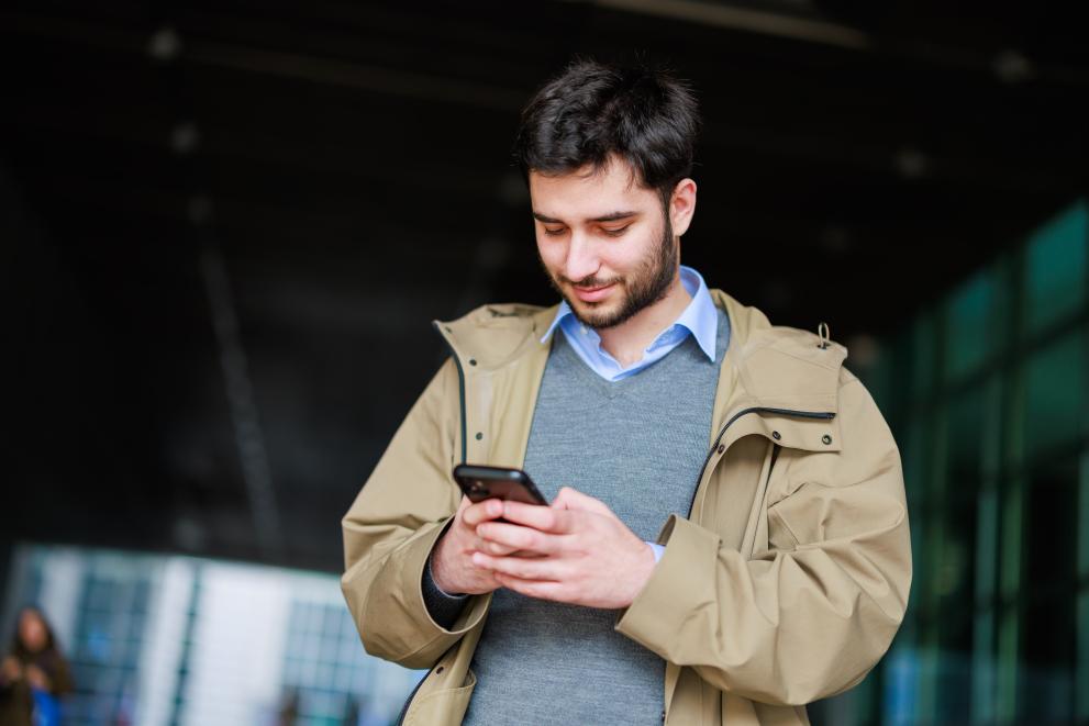 Un bărbat se uită la smartphone-ul său