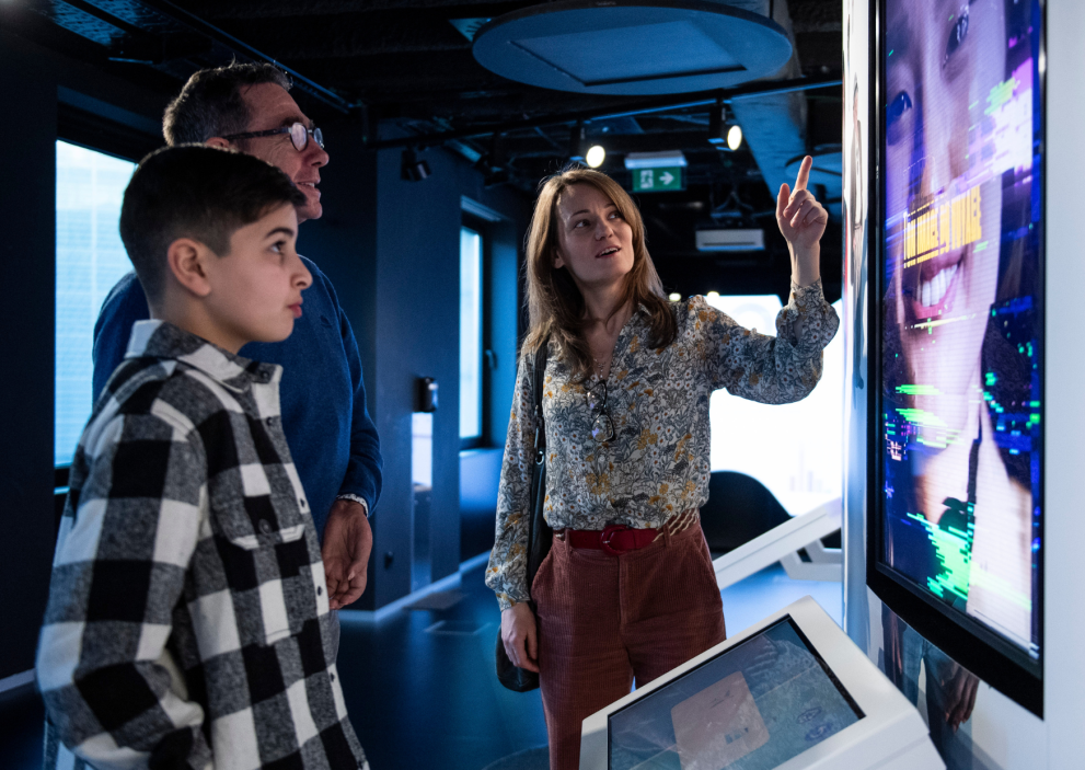 two people at the exhibition looking at a screen and woman explaining and showing something