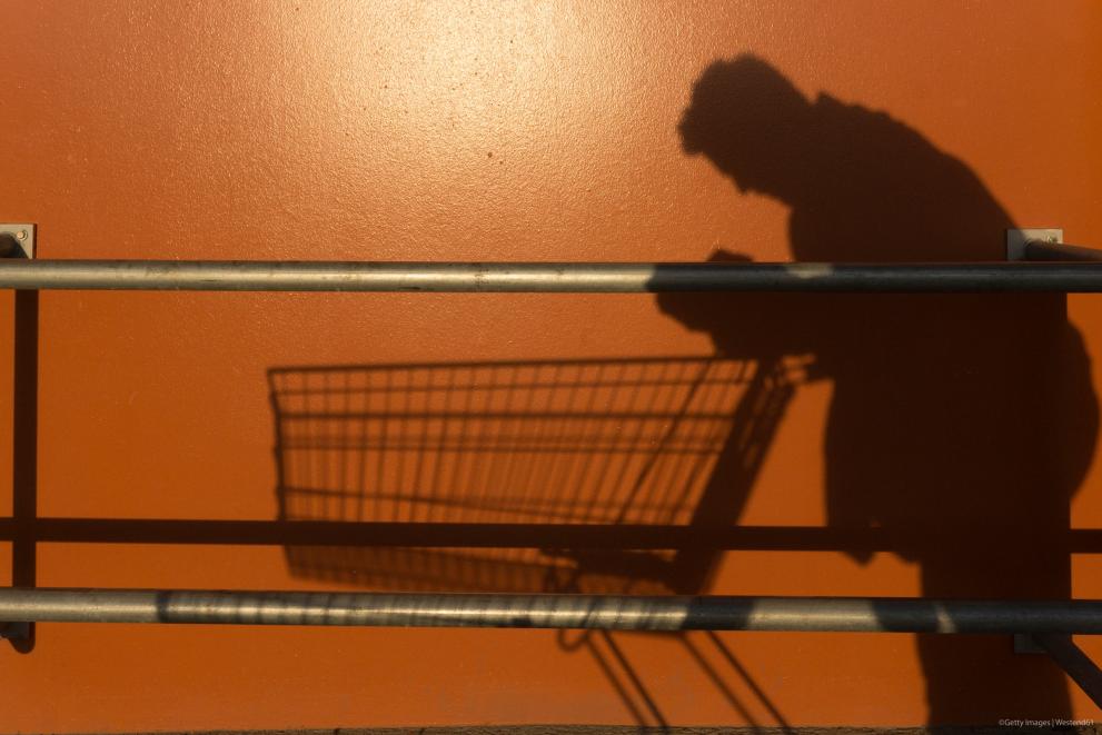 Shadow of a man leaning on an empty shopping trolley