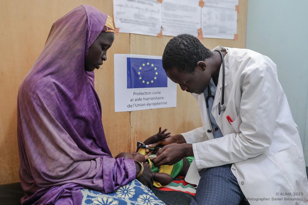 Cameroon: Photo of a humanitarian medical officer examining a child accompanied by her mother.