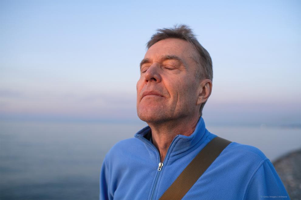 Man with his eyes closed faces towards the sun 
