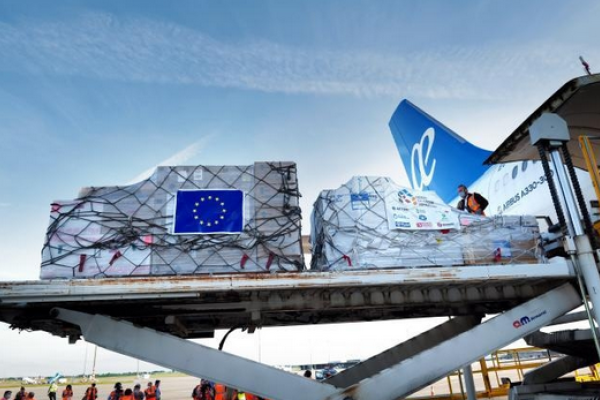 Cargo freight on palettes branded with EU flag being loaded onto an airplane.