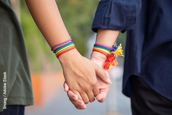 Women holding hands with rainbow bracelets
