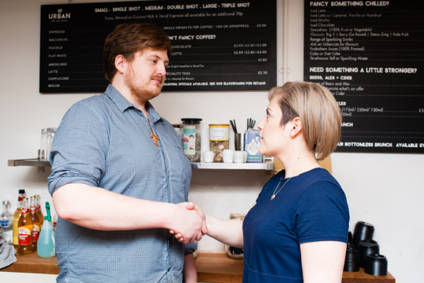 An employer and his employee in a coffee shop shaking hands in agreement