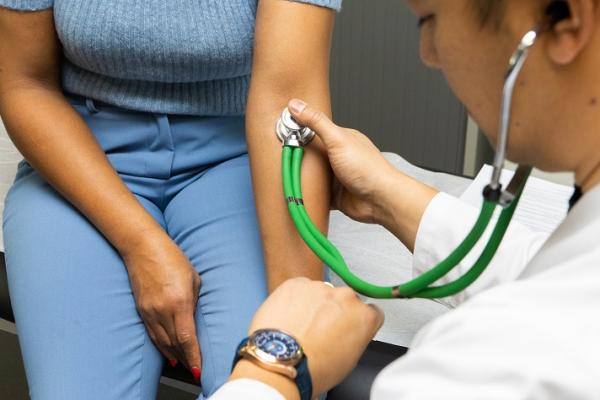 A doctor uses a stethoscope on a patient's arm