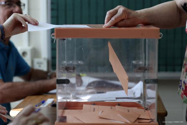 A person putting their vote into a ballot box.