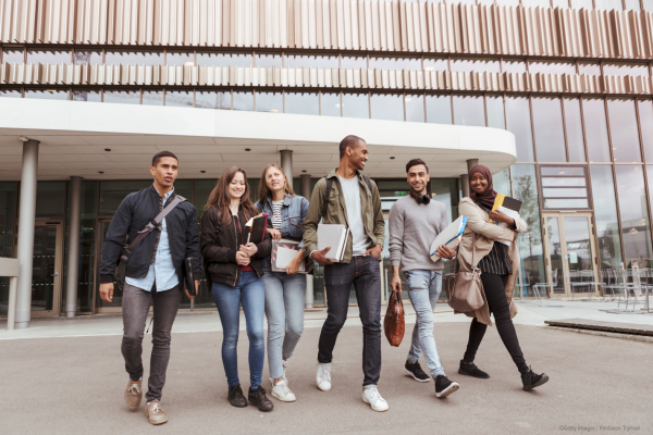 multi-ethnic university students walking against building in campus